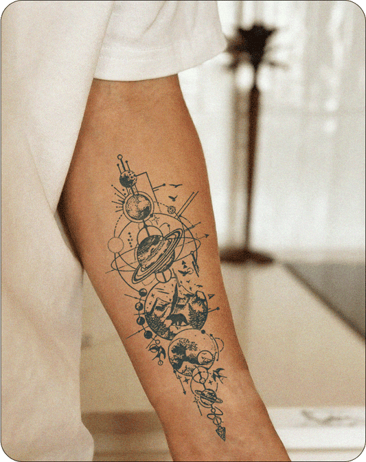 A forearm tattoo showcasing an elaborate vertical design with celestial and nature motifs, including planets, Saturn with rings, geometric patterns, mountain landscapes, birds, and forest imagery in a fine line blackwork style