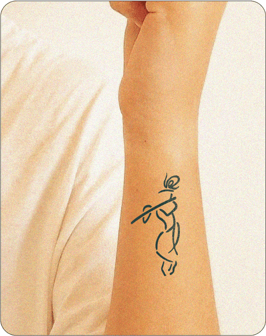 A minimalist line drawing tattoo of Lord Krishna playing the flute, depicted on the inner forearm. The design uses simple, flowing black lines to suggest the figure of Krishna with a topknot and a flute held to the lips, capturing the essence of the deity in an elegant and abstract style.